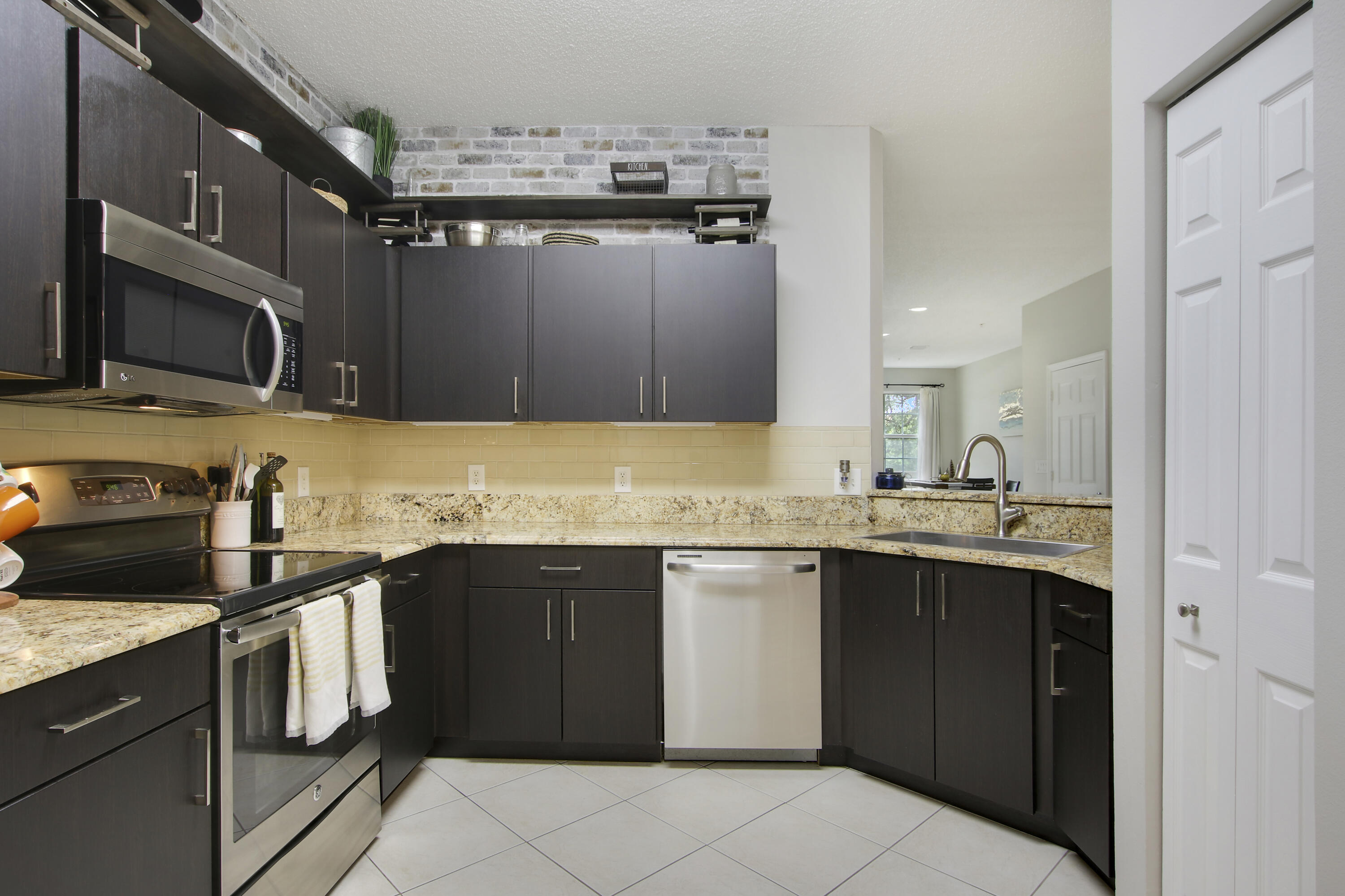 115 Lighthouse Circle, Unit D Tequesta, FL 33469 - Photo 8 of 28 a kitchen with stainless steel appliances granite countertop a sink stove and microwave