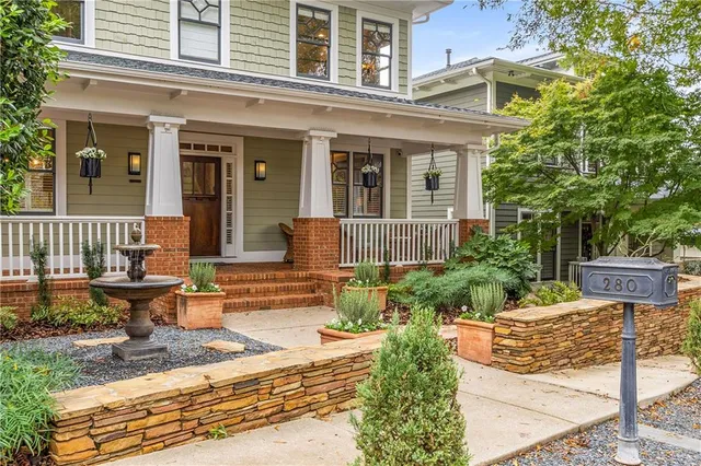 a backyard of a house with a fountain plants and large tree