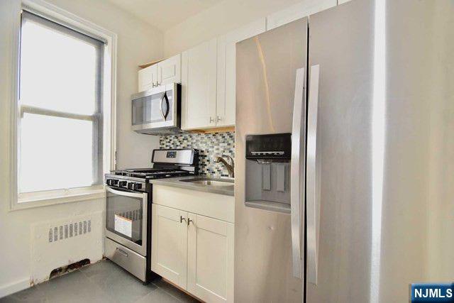 985 Teaneck Road, Unit 1J Teaneck, NJ 07666 - Photo 7 of 10 a kitchen with white cabinets and white appliances
