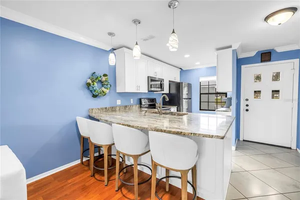a kitchen with granite countertop stainless steel appliances a dining table and chairs