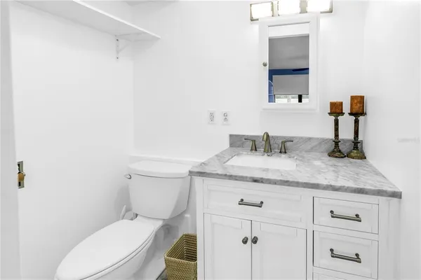a bathroom with a granite countertop toilet sink and mirror
