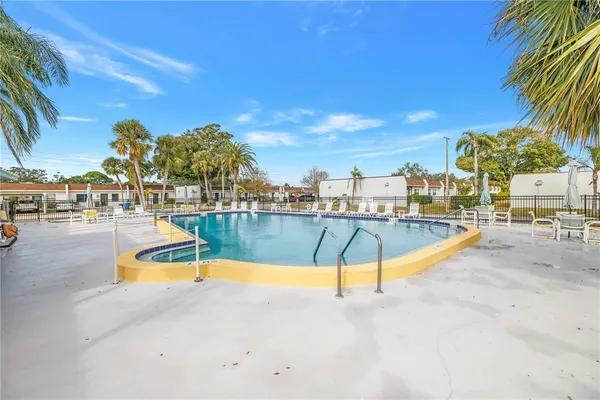a view of a swimming pool with a lounge chair and palm trees
