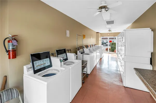 a living room with stainless steel appliances furniture a chandelier and a kitchen view