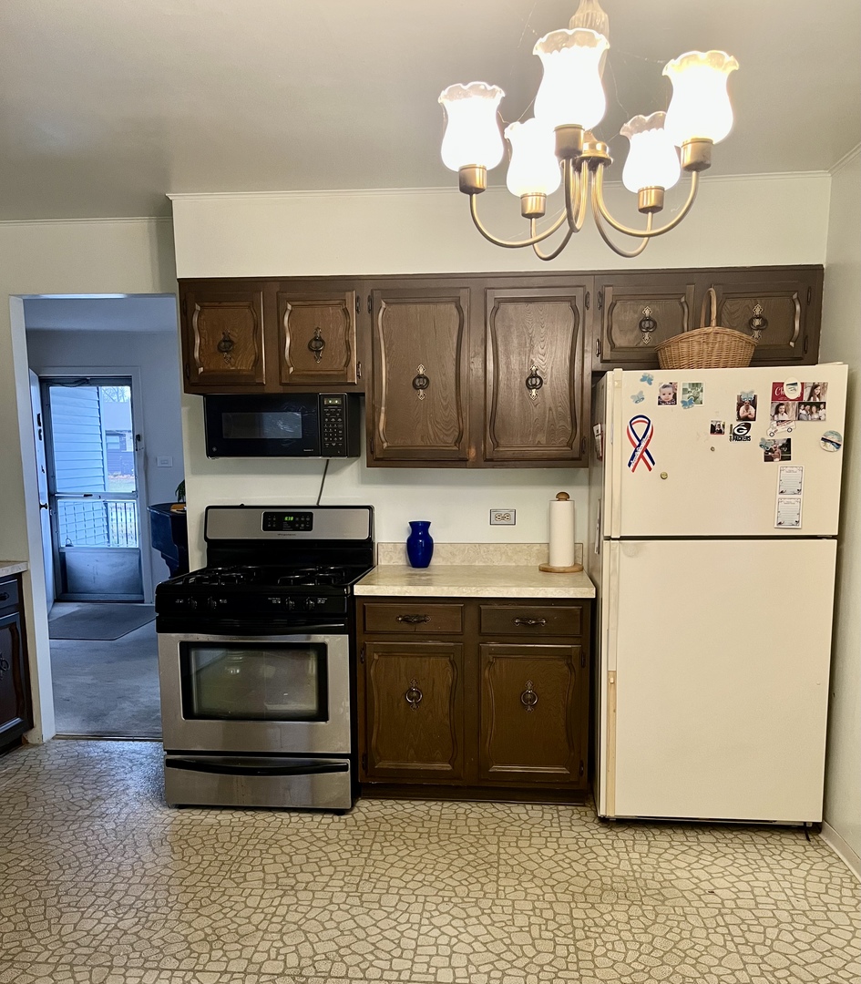 2601 George Street Rolling Meadows, IL 60008 - Photo 2 of 12 a kitchen with a refrigerator a stove top oven cabinets and a dining table