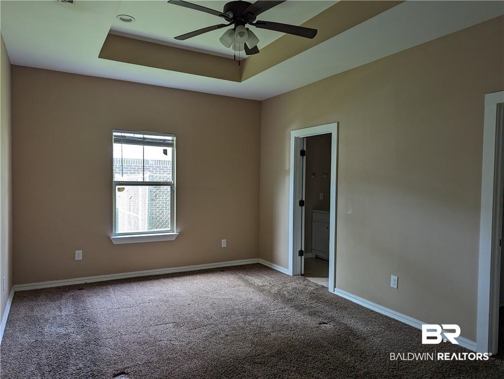 659 Bond Street Mobile, AL 36607 - Photo 6 of 10 Carpeted empty room featuring ceiling fan and a tray ceiling