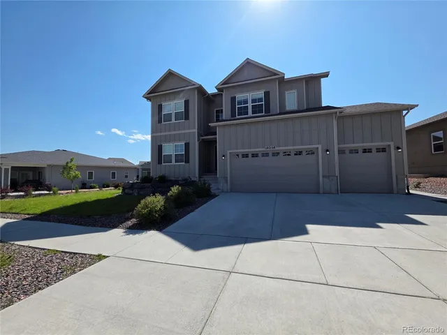 a view of a house with a yard and large trees