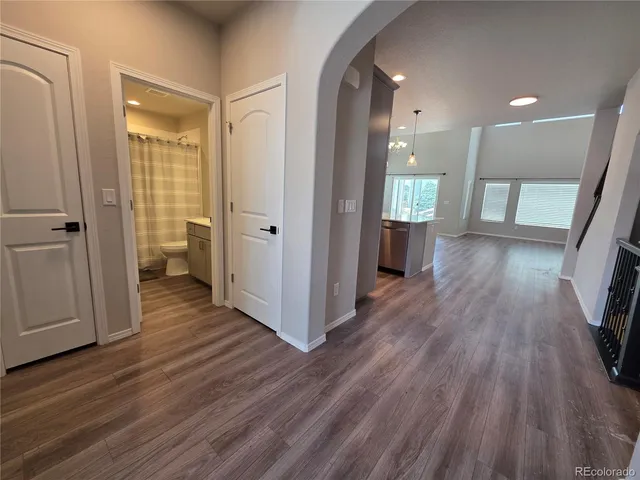 a view of a hallway with wooden floor and a bathroom