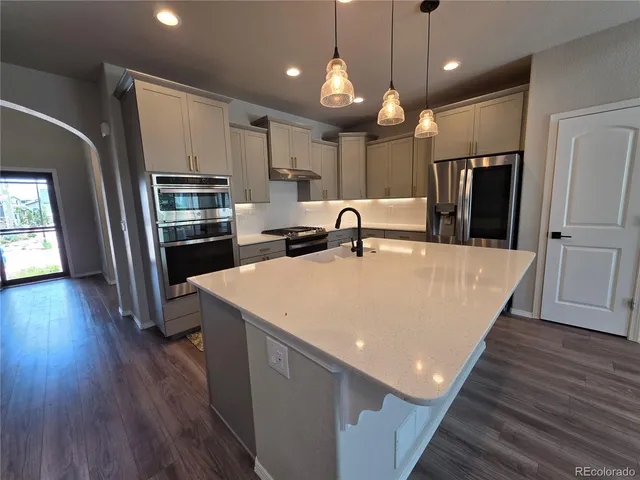 a large kitchen with stainless steel appliances a kitchen island a hardwood floor and a window