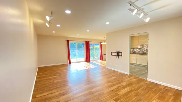 a view of an empty room with wooden floor and a window