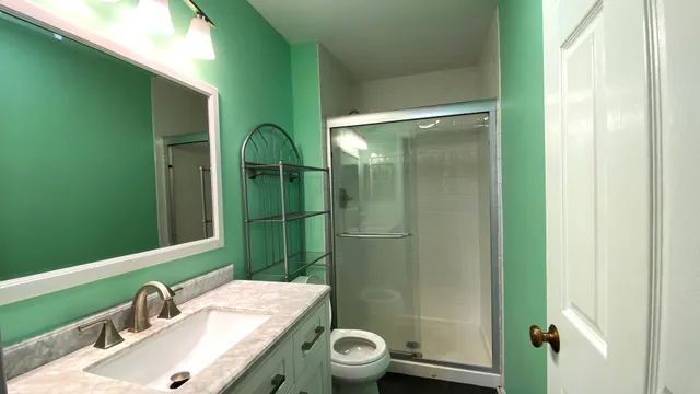 a bathroom with a granite countertop sink toilet and shower