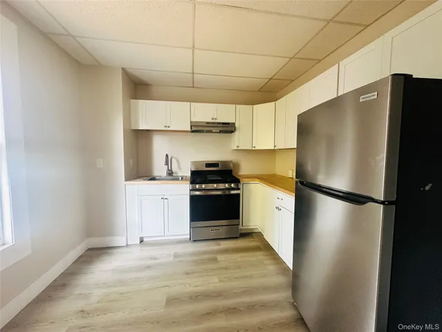 a kitchen with stainless steel appliances a refrigerator sink and white cabinets