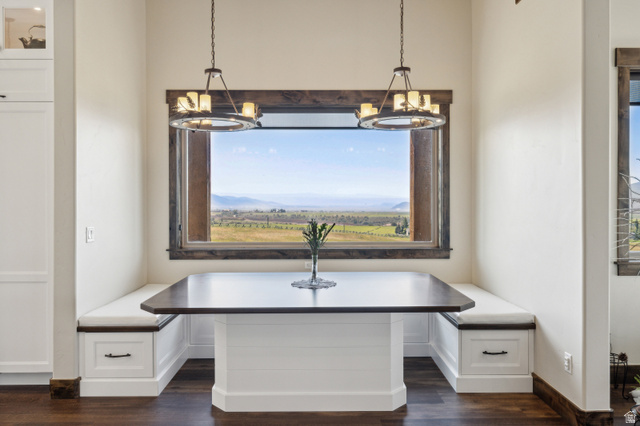 6117 North Rocky Ridge Road Peoa, UT 84061 - Photo 14 of 82 Built-in dining nook with integrated storage, wood-finish flooring, two hanging chandeliers, and a large window with a distant landscape