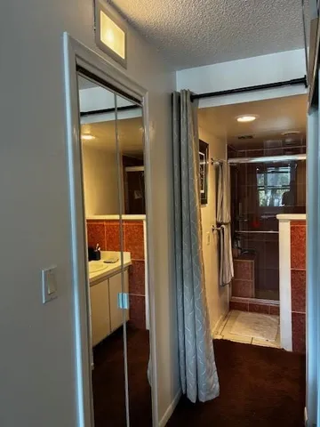 a view of a hallway with wooden floor and a bathroom