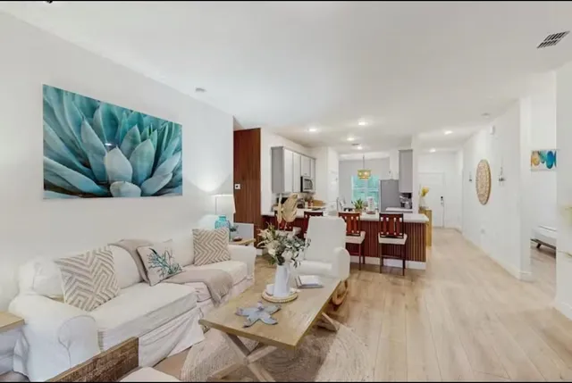 a living room with furniture kitchen view and a wooden floor
