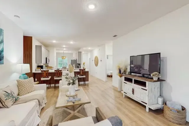 a living room with furniture a flat screen tv and a wooden floor