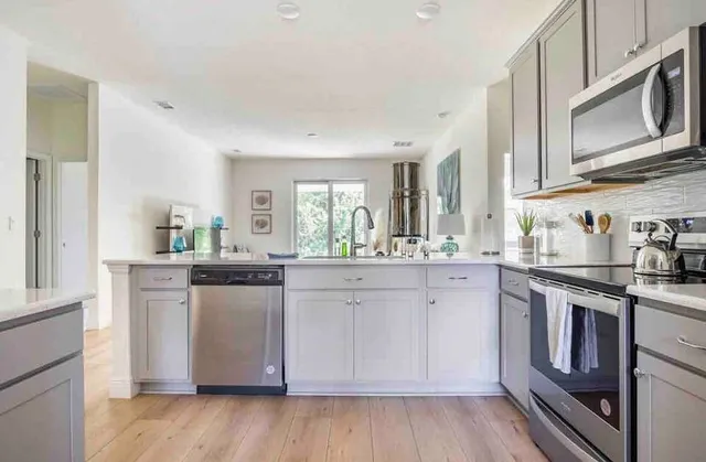 a kitchen with stainless steel appliances granite countertop a stove a sink dishwasher and microwave with wooden floor