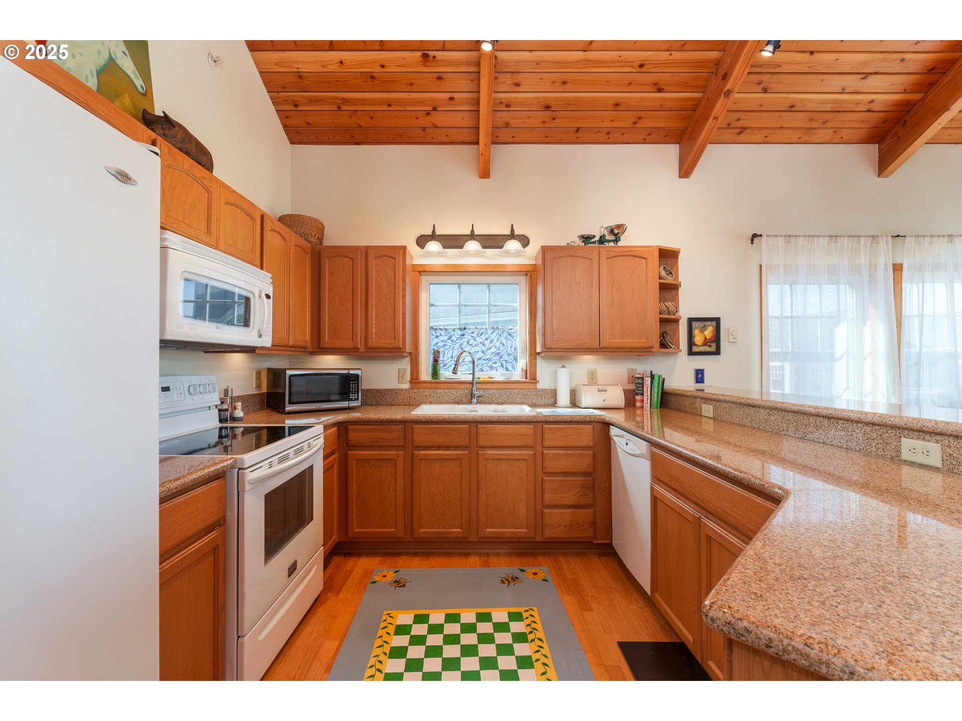 1327 Village Loop Bandon, OR 97411 - Photo 14 of 38 a kitchen with stainless steel appliances granite countertop a stove a sink and a refrigerator