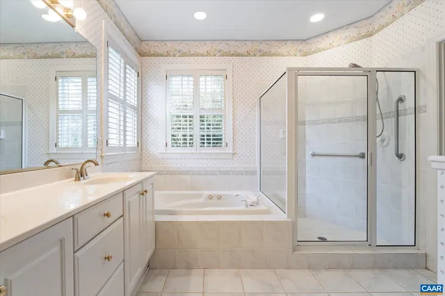 a bathroom with a granite countertop sink mirror bathtub and next to a window