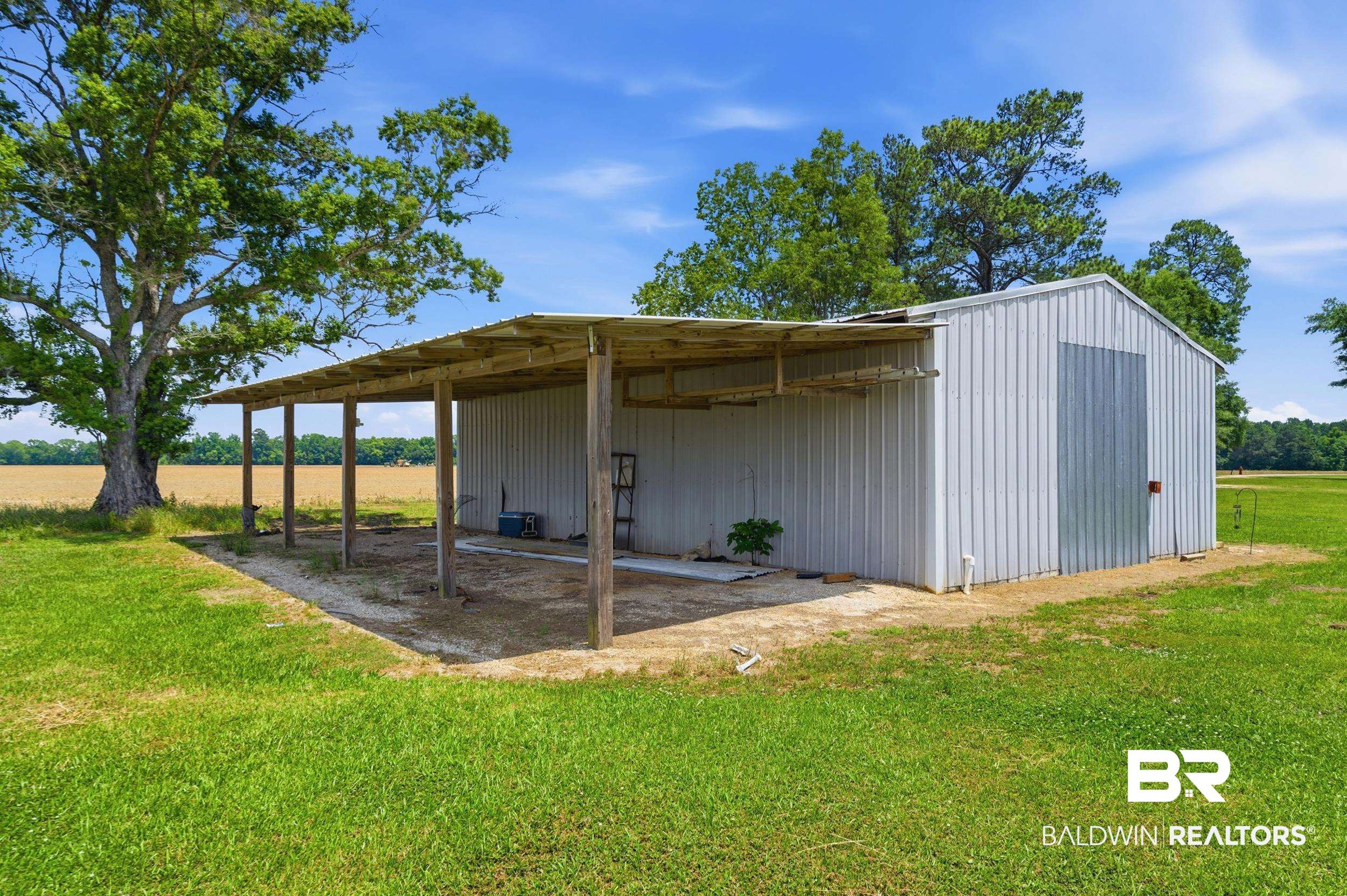 926 Tumbling Lane Atmore, AL 36502 - Photo 45 of 56 Metal outbuilding featuring a covered lean-to, corrugated metal siding, and a large metal door