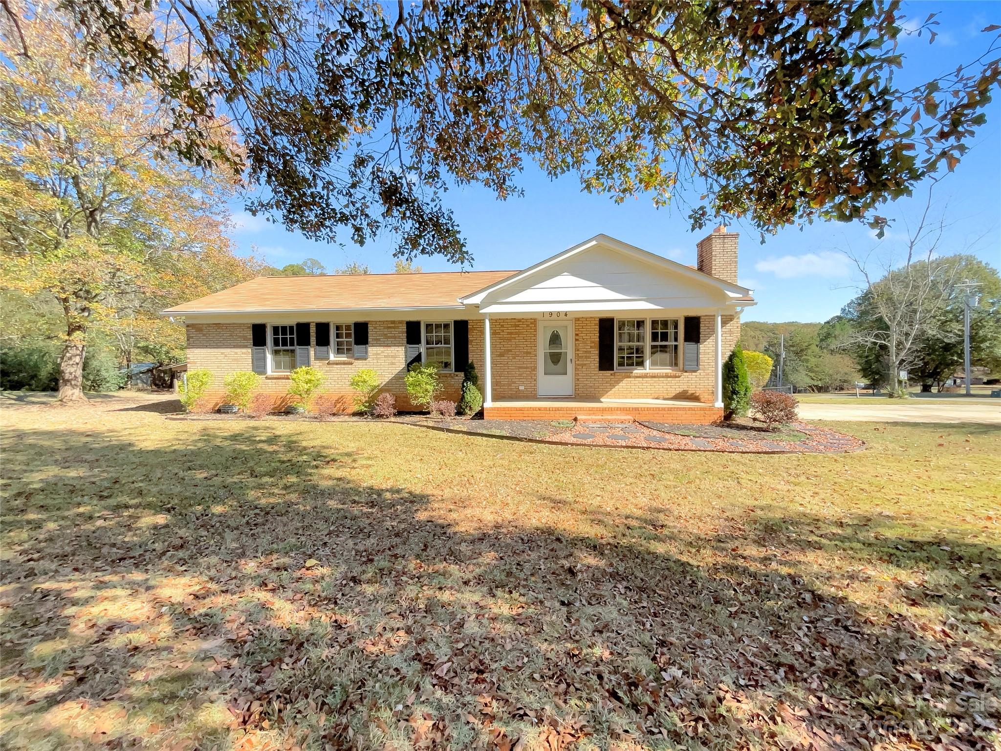 a front view of a building with a yard and trees