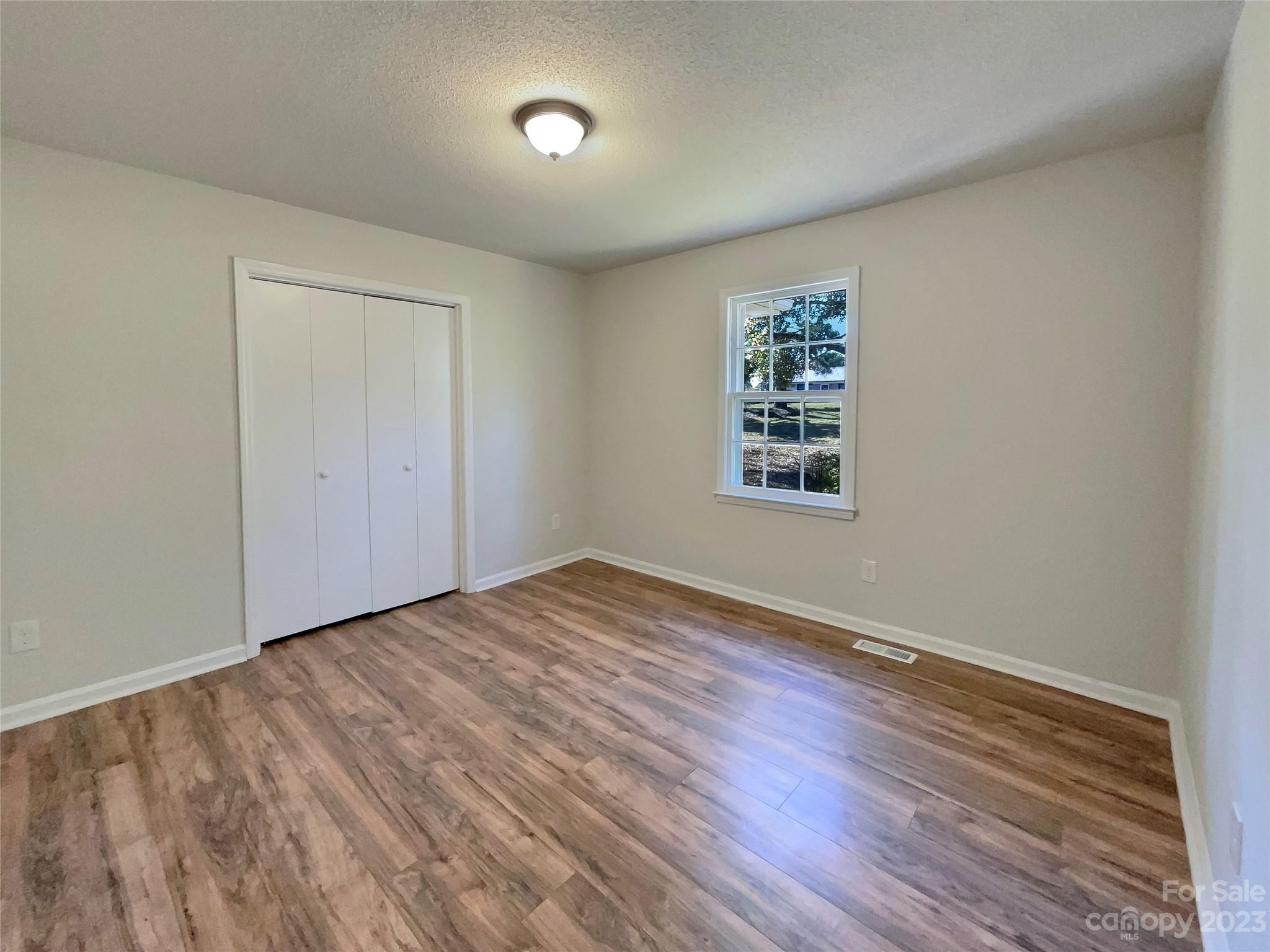 1904 Bess Town Road Bessemer City, NC 28016 - Photo 14 of 18 an empty room with wooden floor and windows
