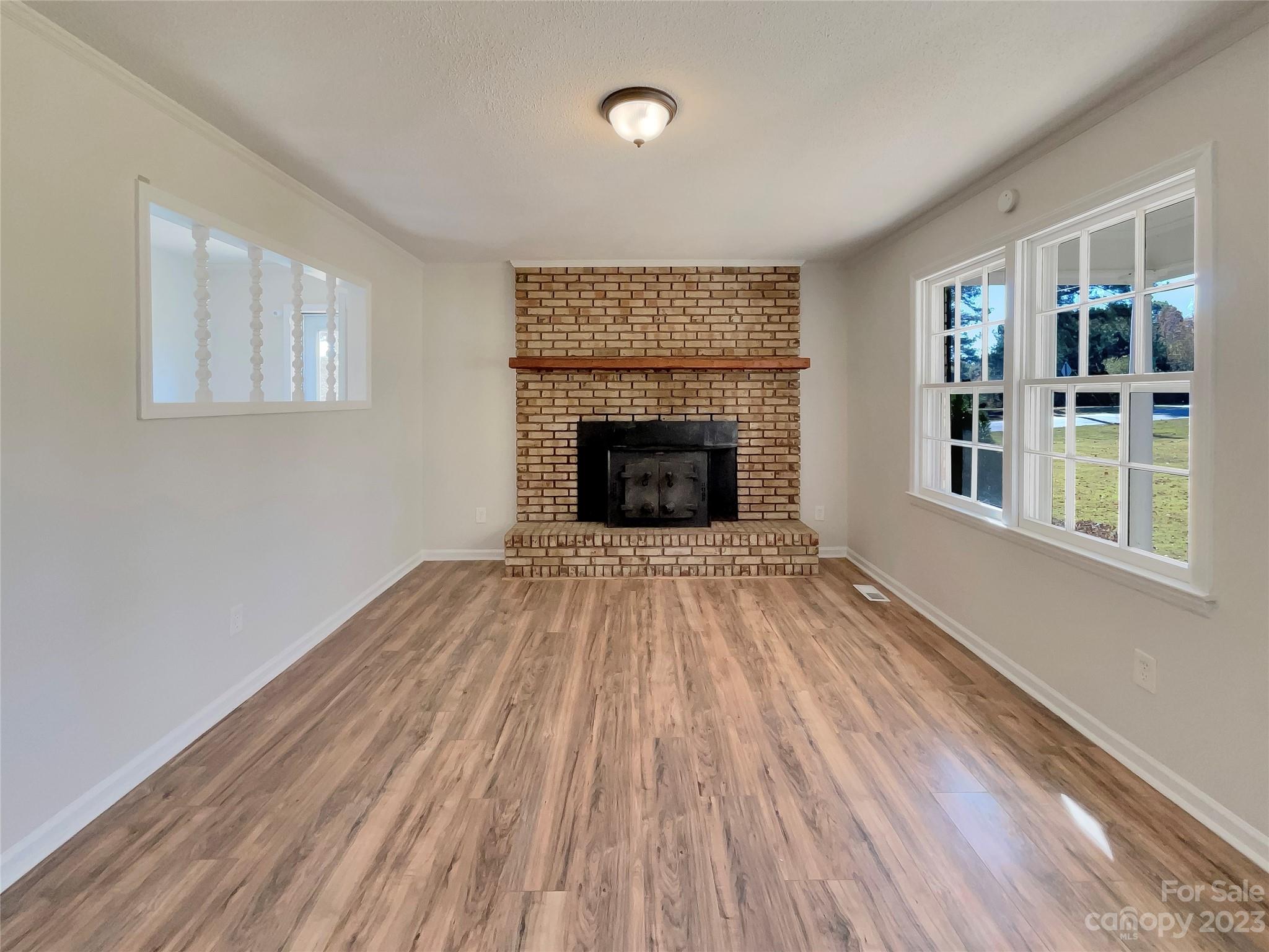 1904 Bess Town Road Bessemer City, NC 28016 - Photo 3 of 18 a view of an empty room with wooden floor fireplace and a window