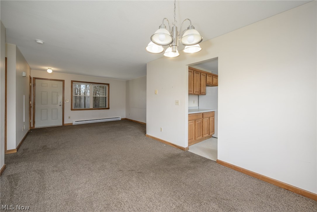 8464-8446 Tallmadge Road Diamond, OH 44412 - Photo 7 of 39 Unfurnished room with light carpet, a chandelier, and a baseboard heating unit
