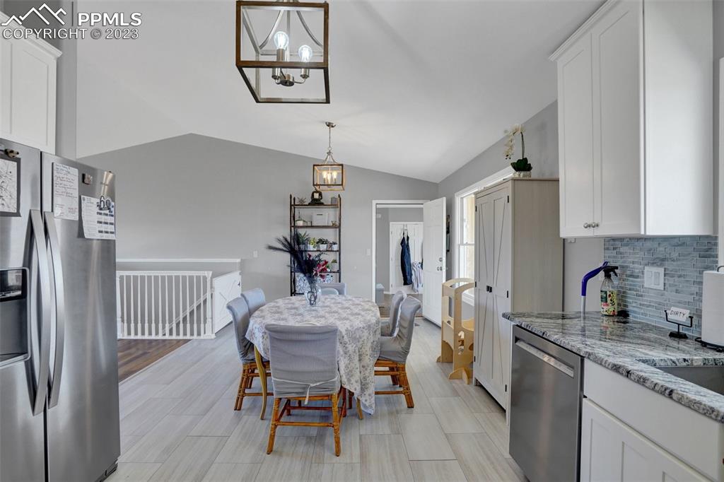 3805 Curtis Road Peyton, CO 80831 - Photo 14 of 48 a kitchen with stainless steel appliances granite countertop a dining table chairs refrigerator and cabinets