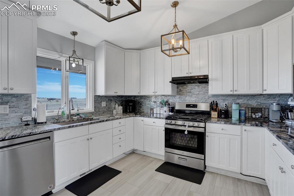3805 Curtis Road Peyton, CO 80831 - Photo 19 of 48 a kitchen with stainless steel appliances granite countertop a sink a stove and cabinets