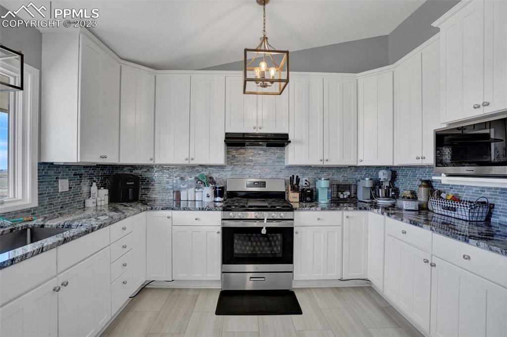 3805 Curtis Road Peyton, CO 80831 - Photo 21 of 48 a kitchen with granite countertop white cabinets and stainless steel appliances