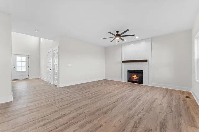 a view of an empty room with wooden floor and a fireplace
