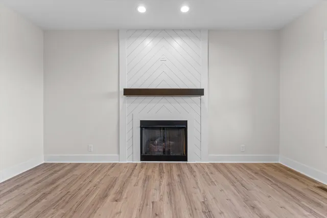 an empty room with wooden floor and fireplace