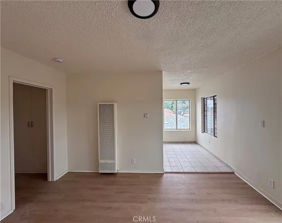 a view of an empty room with wooden floor and window