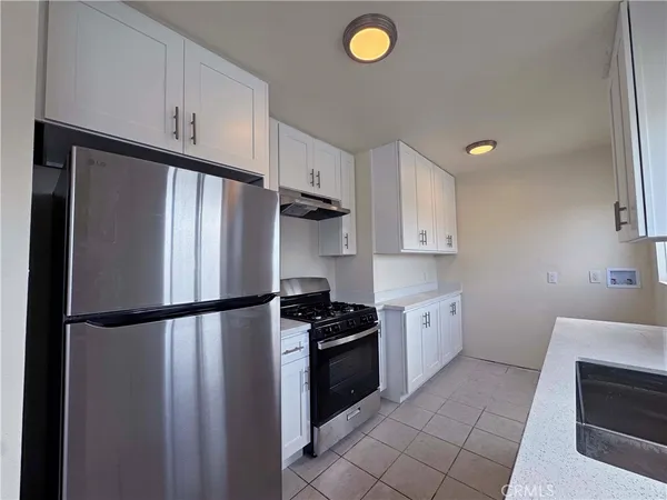 a kitchen with a refrigerator a stove top oven and cabinets