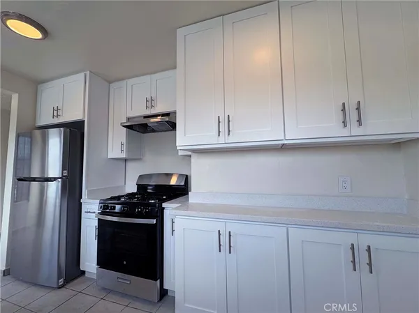 a kitchen with white cabinets and refrigerator