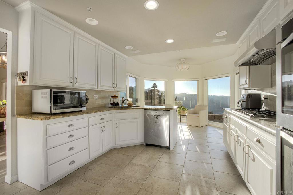 31220 Aquaduct Road Bonsall, CA 92003 - Photo 14 of 36 a kitchen with a stove and white cabinets