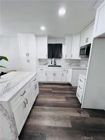 a large white kitchen with stainless steel appliances granite countertop lots of white cabinets a stove and sink