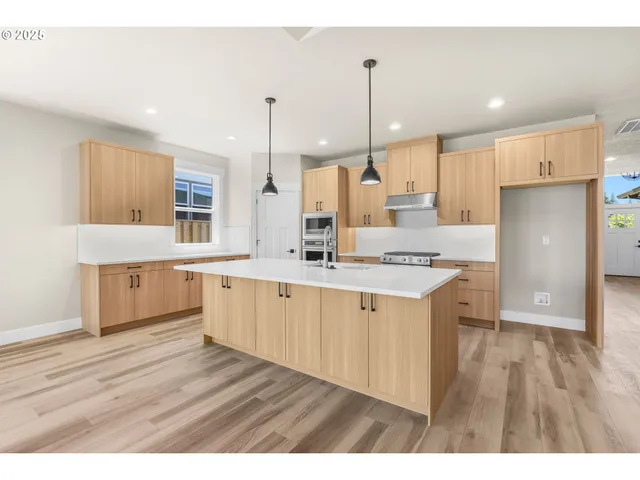 a large kitchen with a lot of counter space and wooden floor