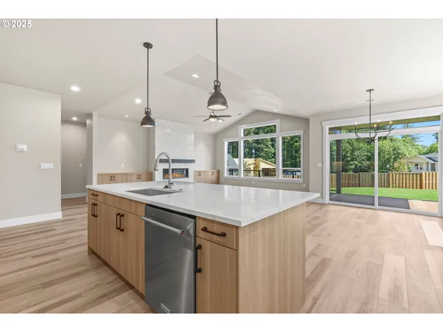 a open kitchen with kitchen island a sink appliances and a large window