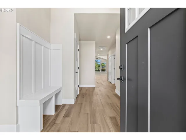 a hallway with wooden floor windows and a bathroom