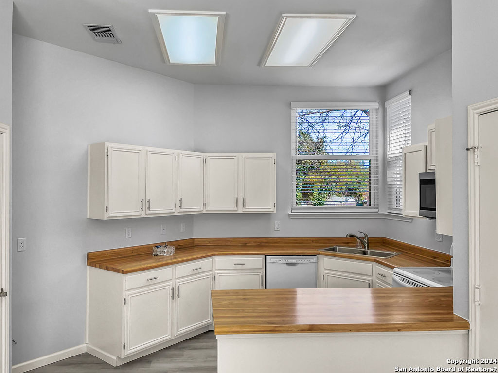 13211 Huntsman Road San Antonio, TX 78249 - Photo 11 of 33 a kitchen with stainless steel appliances granite countertop a sink a stove and a granite counter tops with white cabinets