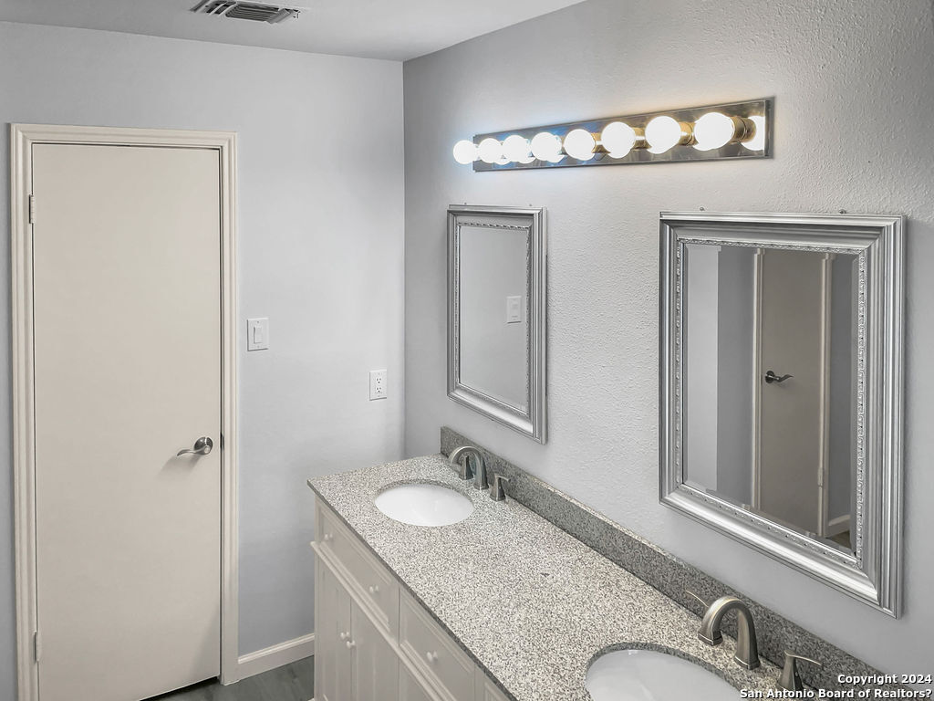 13211 Huntsman Road San Antonio, TX 78249 - Photo 17 of 33 a bathroom with a granite countertop sink and a mirror
