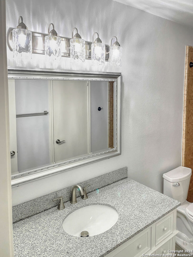 13211 Huntsman Road San Antonio, TX 78249 - Photo 18 of 33 a bathroom with a granite countertop sink and a mirror