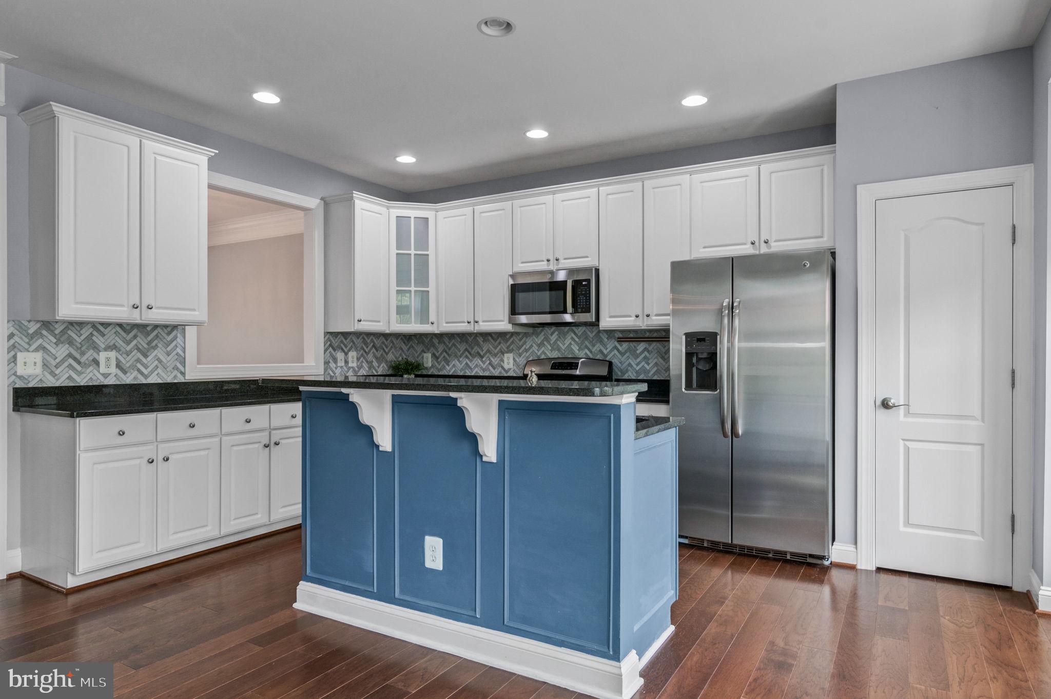 5893 Riverside Drive Woodbridge, VA 22193 - Photo 10 of 36 a kitchen with kitchen island granite countertop wooden floors white cabinets and stainless steel appliances