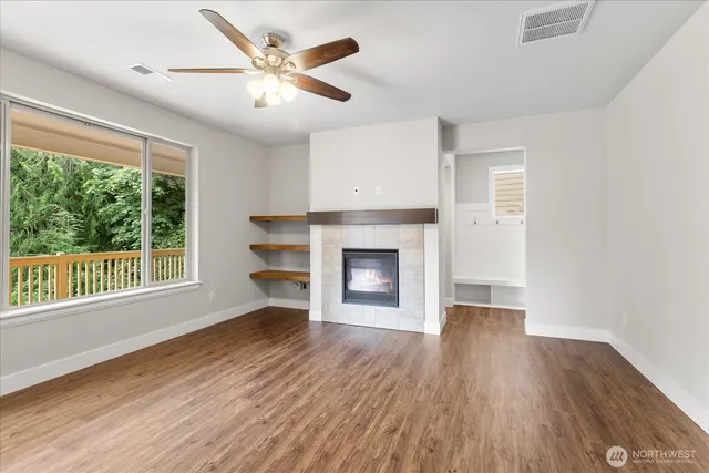 a view of an empty room with a window and wooden floor