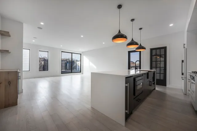 a kitchen with granite countertop a stove a sink a refrigerator and white cabinets with wooden floor