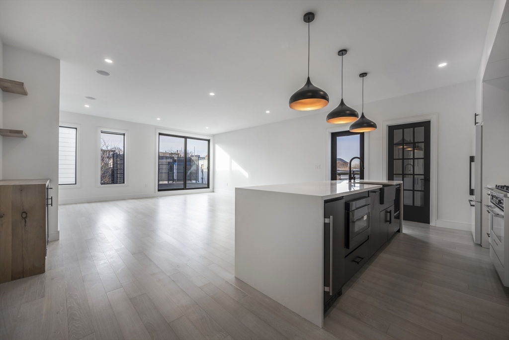14 B Geneva Street, Unit 1 Boston, MA 02128 - Photo 2 of 4 a kitchen with granite countertop a stove a sink a refrigerator and white cabinets with wooden floor
