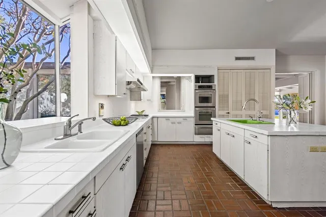 a large white kitchen with stainless steel appliances kitchen island granite countertop a sink and dishwasher with white cabinets