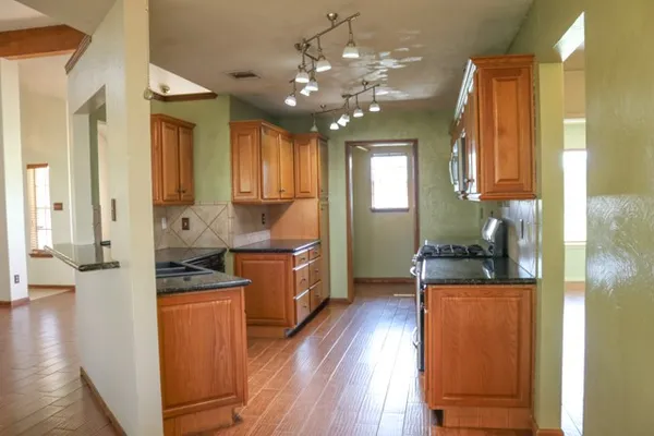 a kitchen with kitchen island granite countertop a refrigerator and wooden floor