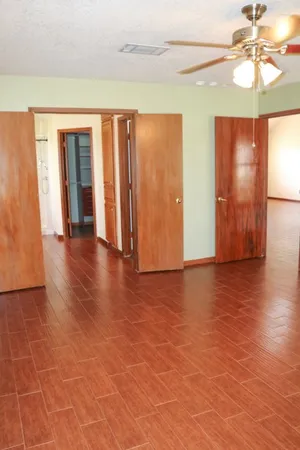 a view of an empty room with window and wooden floor